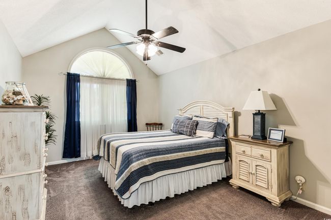 Bedroom featuring ceiling fan, dark carpet, visible vents, vaulted ceiling, and baseboards | Image 23