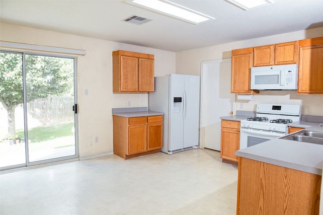 Kitchen featuring white appliances, light countertops, and brown cabinetry | Image 7