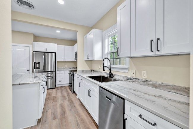 Kitchen with a sink, white cabinetry, stainless steel appliances, and visible vents | Image 9