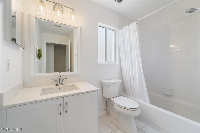 Bathroom with vanity, toilet, shower / bath combo, tile patterned floors, and baseboards | Image 12