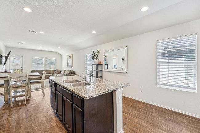 Kitchen with visible vents, dark brown cabinets, open floor plan, wood finished floors, and a sink | Image 10