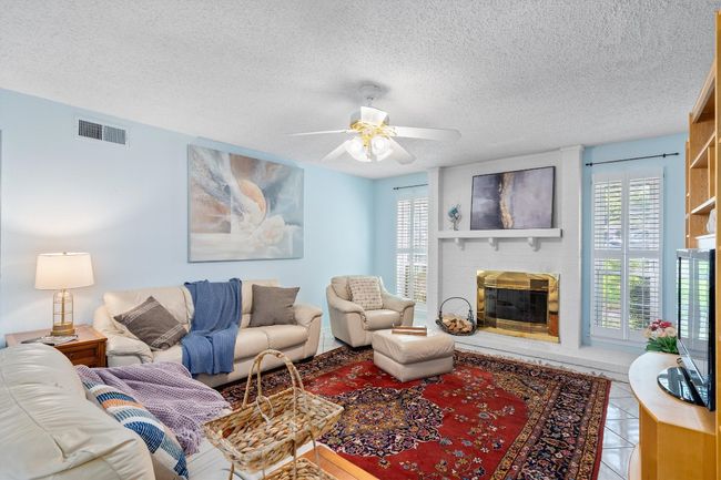 Living room with a textured ceiling, a healthy amount of sunlight, and visible vents | Image 7