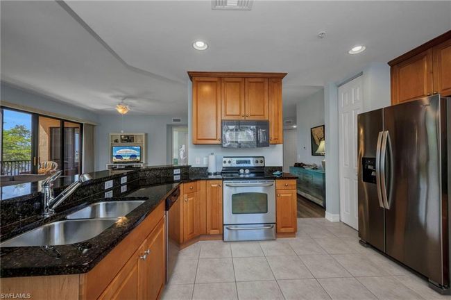 Kitchen featuring appliances with stainless steel finishes, dark stone countertops, light tile patterned floors, recessed lighting, and a peninsula | Image 14