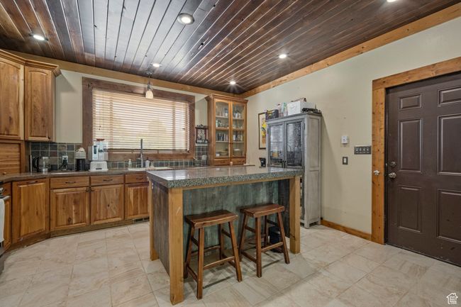 Kitchen with recessed lighting, a kitchen island, dark countertops, wood ceiling, and a breakfast bar | Image 11