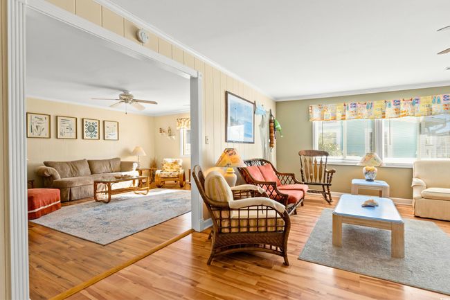 Living room featuring wood-type flooring, ceiling fan, and crown molding | Image 7