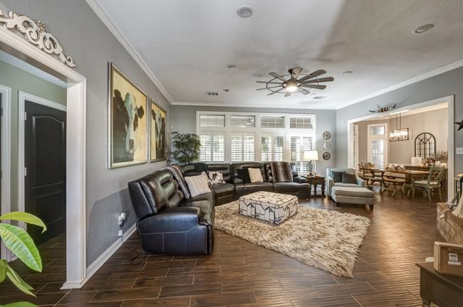 Living area with crown molding, visible vents, a ceiling fan, and wood tiled floor | Image 10