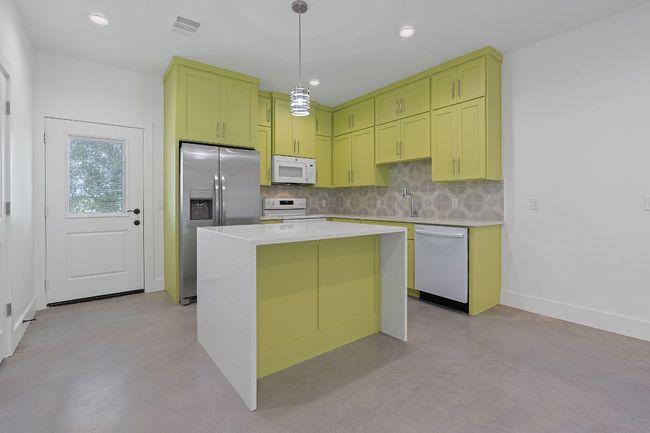 Kitchen with green cabinetry, concrete floors, and white appliances | Image 13