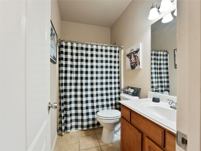 Full bath featuring vanity, toilet, tile patterned flooring, and curtained shower | Image 15