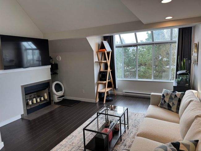 Living room featuring baseboards, baseboard heating, wood finished floors, and a tile fireplace | Image 9