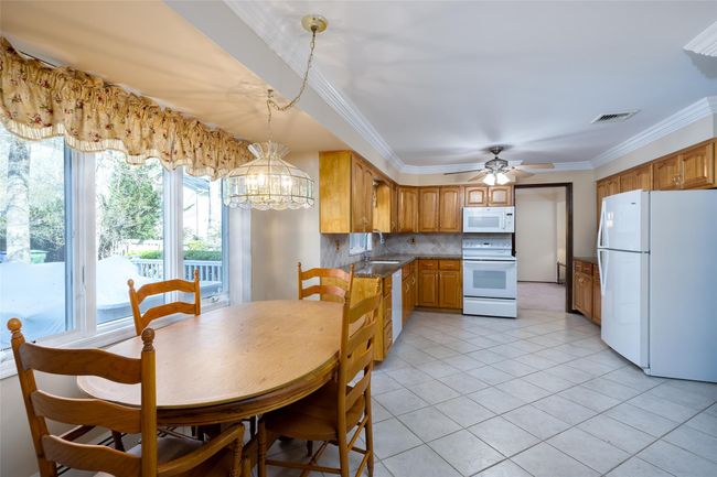 Dining area with crown molding, light tile patterned flooring, visible vents, and ceiling fan with notable chandelier | Image 18