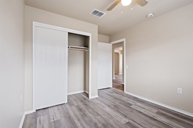 Unfurnished bedroom with wood finished floors, a closet, ceiling fan, and arched walkways | Image 11