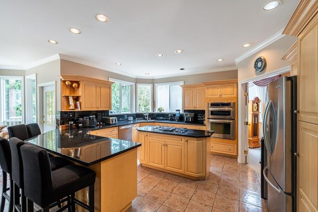 Kitchen featuring a peninsula, decorative backsplash, appliances with stainless steel finishes, and light brown cabinets | Image 13