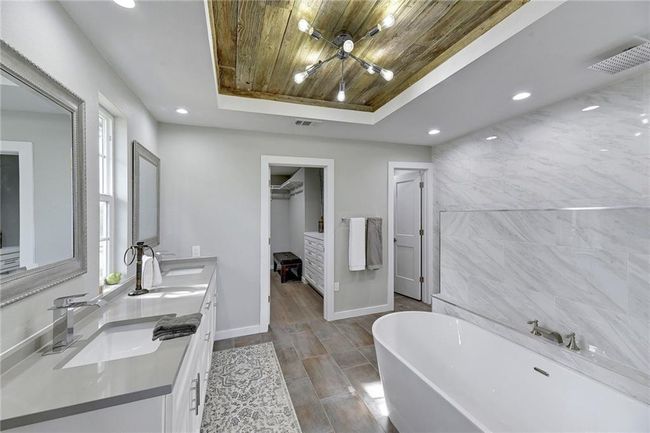 Bathroom featuring a raised ceiling, wood ceiling, a freestanding bath, double vanity, and recessed lighting | Image 12