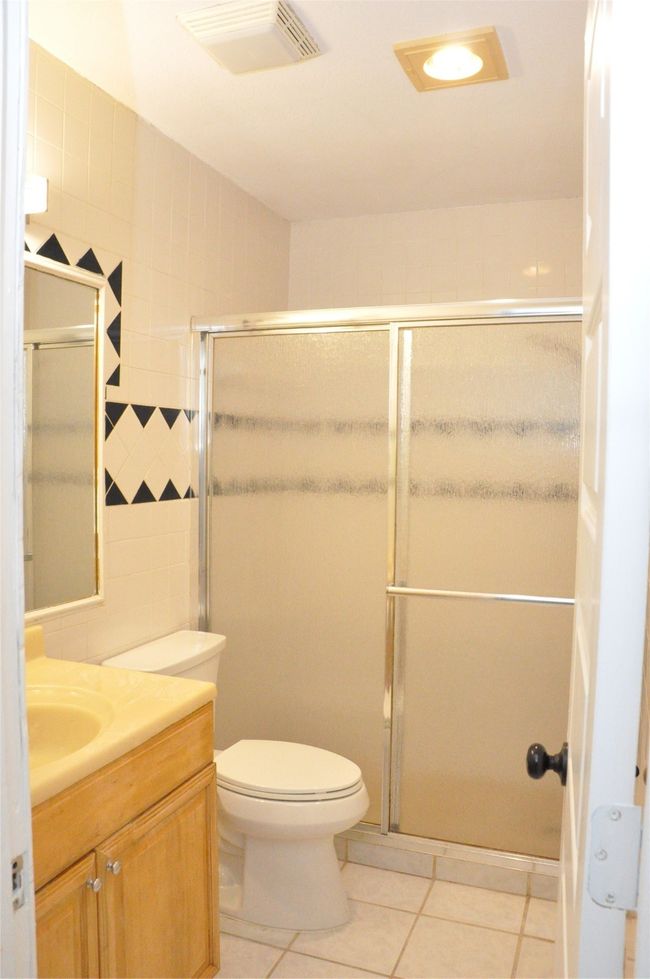 Full bathroom featuring tile walls, a shower stall, vanity, tile patterned floors, and visible vents | Image 22