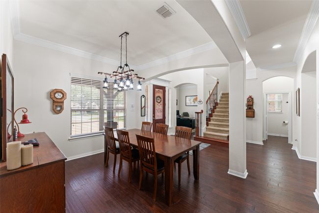 Dining area featuring arched walkways, healthy amount of natural light, dark wood-style floors, a chandelier, and crown molding | Image 13