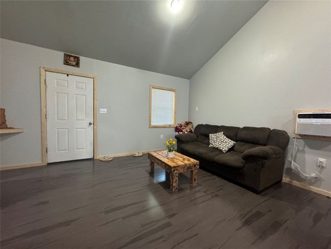Living area with lofted ceiling, dark wood-style floors, and an AC wall unit | Image 6