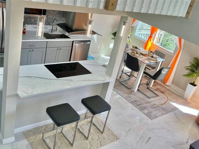 Kitchen with marble finish floor, black electric cooktop, backsplash, dishwasher, and baseboards | Image 34