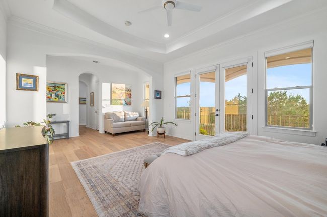 Bedroom featuring access to outside, arched walkways, crown molding, light wood finished floors, and a raised ceiling | Image 14