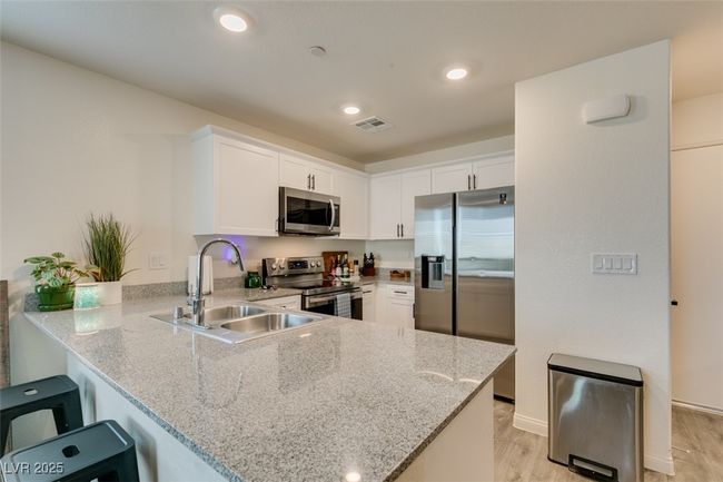 Kitchen with a peninsula, white cabinetry, visible vents, appliances with stainless steel finishes, and a sink | Image 14