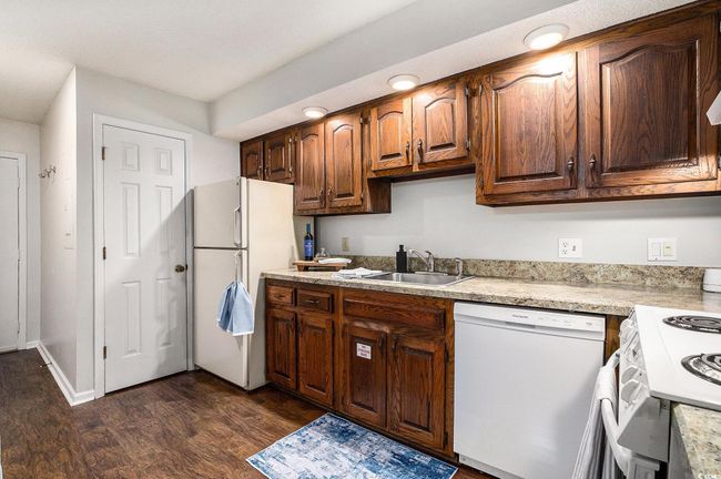 Kitchen with white appliances, light countertops, and dark wood-style flooring | Image 10