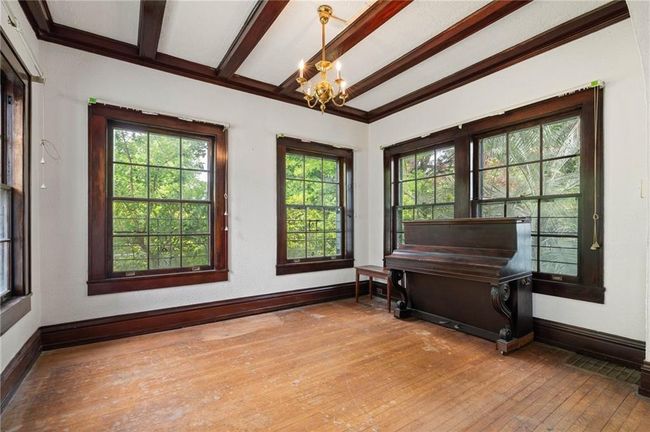 Living area featuring a wealth of natural light, hardwood flooring, beam ceiling, and a chandelier. | Image 7