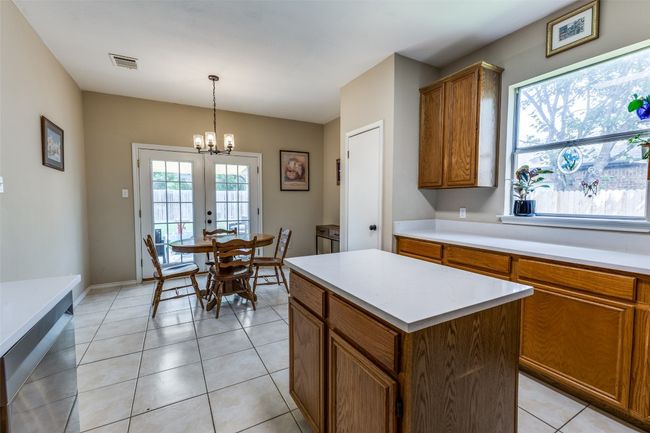 Kitchen featuring plenty of natural light, brown cabinets, a chandelier, and quartz countertops | Image 9