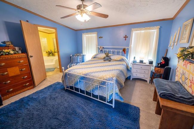 Bedroom featuring ensuite bath, crown molding, a textured ceiling, and carpet | Image 9