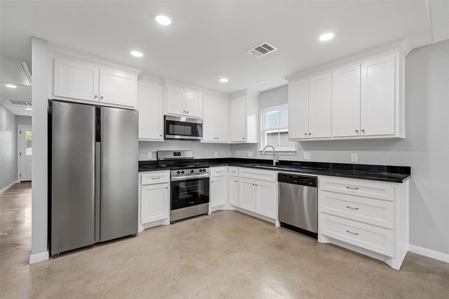 Kitchen featuring visible vents, stainless steel appliances, white cabinets, and baseboards | Image 4