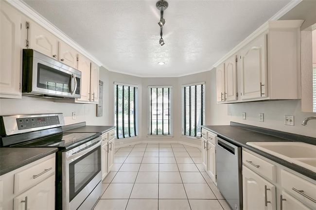 Kitchen with charming breakfast nook lined by bay windows | Image 5