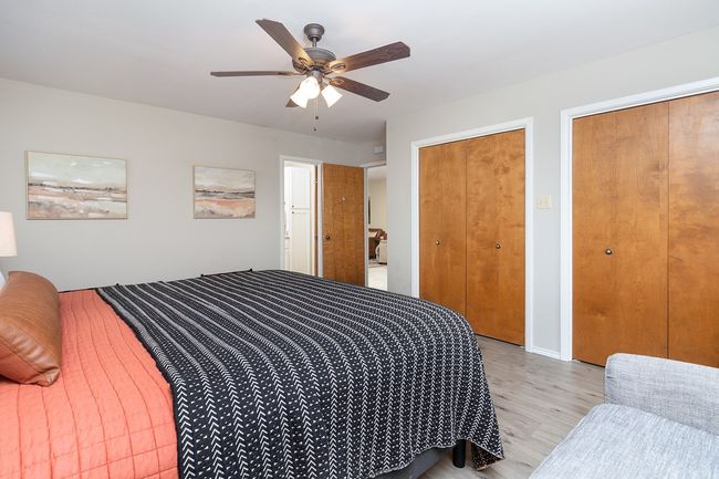 Bedroom featuring light wood finished floors, ceiling fan, and two closets | Image 18