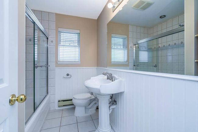 Bathroom featuring a baseboard radiator, wainscoting, tile patterned flooring, visible vents, and shower / bath combination with glass door | Image 18