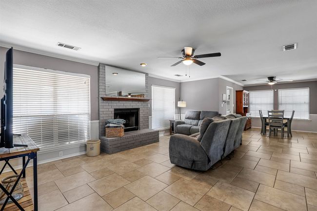 Living room featuring a healthy amount of sunlight, ornamental molding, ceiling fan, and a fireplace | Image 16