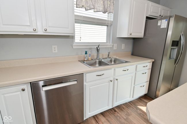 kitchen featuring appliances with stainless steel finishes, a sink, and white cabinetry | Image 22