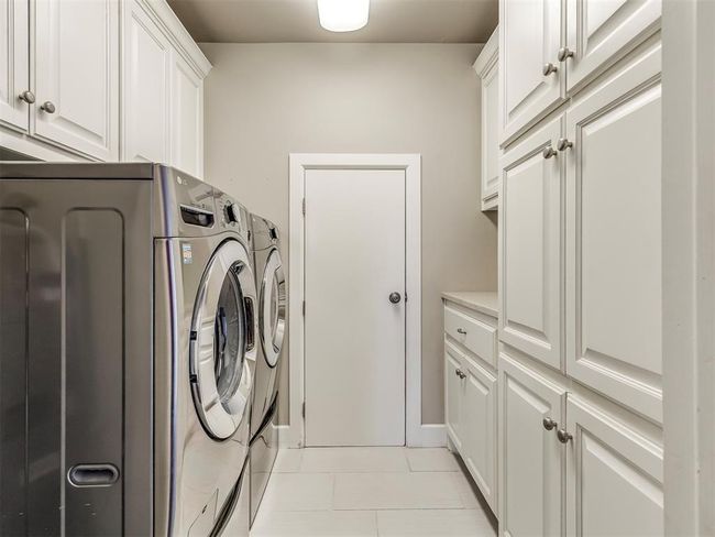 Clothes washing area with cabinet space, washing machine and dryer, and light tile patterned flooring | Image 22