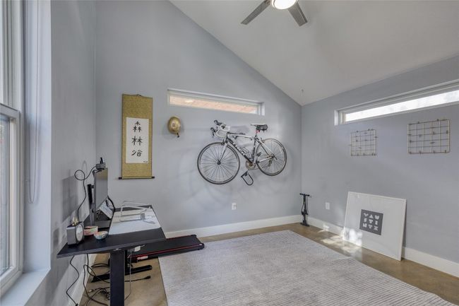 Office area with high vaulted ceiling, a ceiling fan, baseboards, and finished concrete floors | Image 16