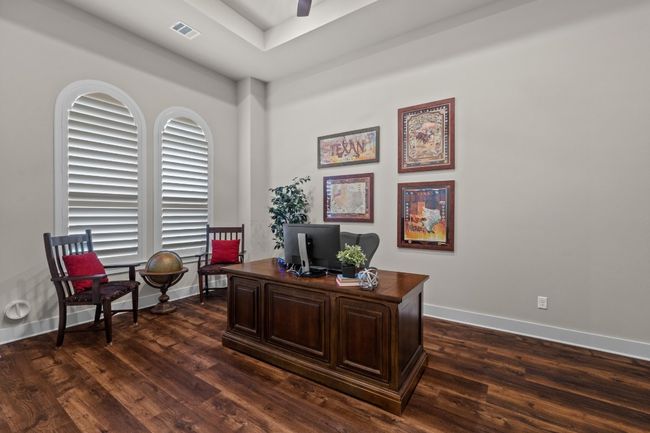 Office space with a ceiling fan, a tray ceiling, visible vents, baseboards, and dark wood-style floors | Image 26