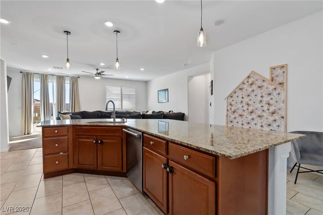 Kitchen featuring dishwasher, open floor plan, a sink, and brown cabinetry | Image 19