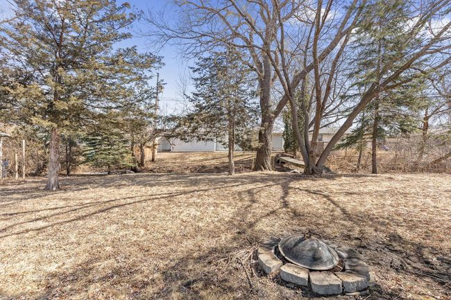 Large back yard with fire pit area across the walking bridge. | Image 24