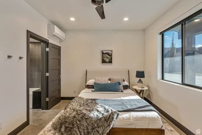 Bedroom featuring recessed lighting, a wall unit AC, concrete floors, and baseboards | Image 61