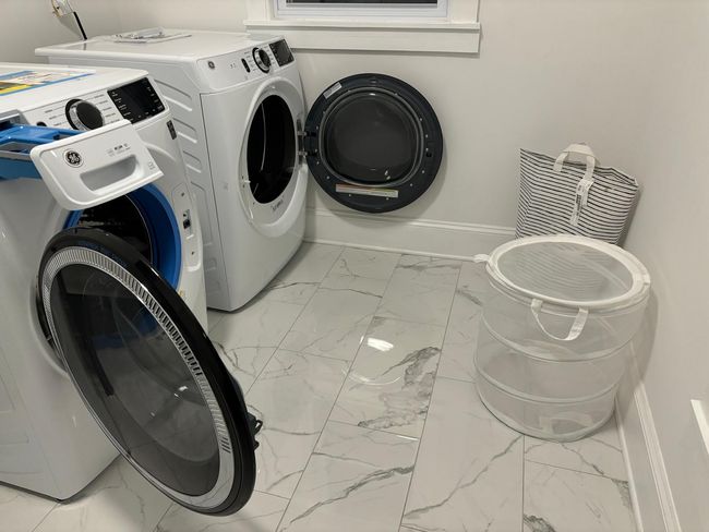 Washroom with marble look tile flooring, baseboards, and washer and dryer | Image 6