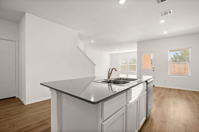 Kitchen featuring stainless steel dishwasher, a sink, visible vents, and light wood-style floors | Image 6