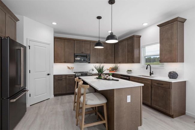 Kitchen with light hardwood / wood-style floors, a kitchen island, stainless steel appliances, decorative light fixtures, and sink | Image 14