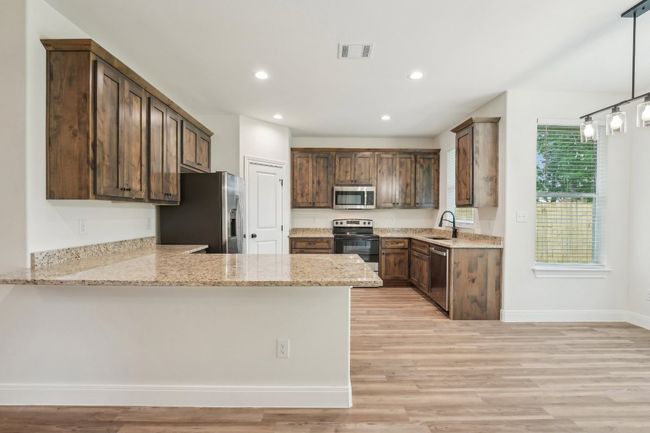 Kitchen with Vinyl Wood Plank floor, visible vents, a sink, a peninsula, and appliances with stainless steel finishes | Image 17