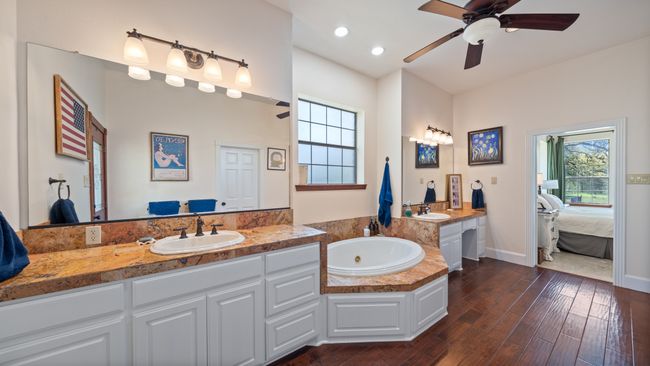 Full bath featuring connected bathroom, a sink, a ceiling fan, wood finished floors, and a bath | Image 20