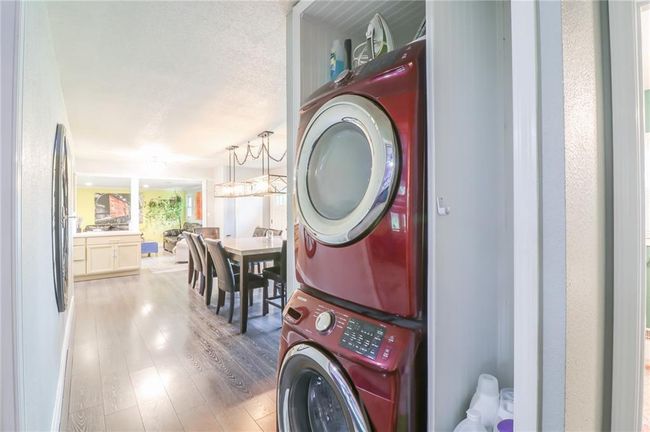 Laundry area with stacked washer / drying machine and wood finished floors | Image 25