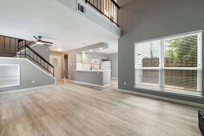 Unfurnished living room with stairs, light wood-style flooring, baseboards, a ceiling fan, and a sink | Image 13