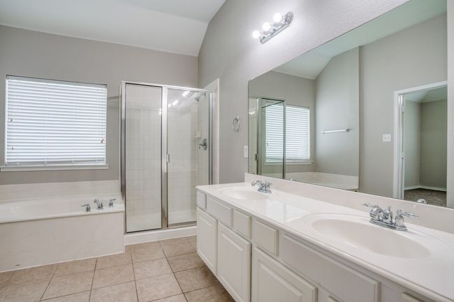 Bathroom with a garden tub, a shower stall, double vanity, tile patterned flooring, and lofted ceiling | Image 12