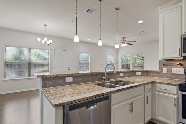 Kitchen featuring a sink, appliances with stainless steel finishes, a peninsula, tasteful backsplash, and a ceiling fan | Image 14