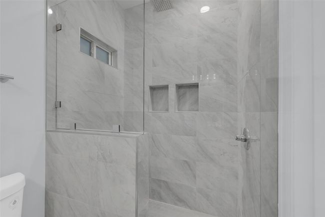 Modern shower with sleek gray marble tiles, glass enclosure, and built-in shelving. | Image 30