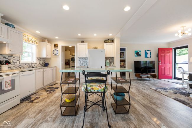 kitchen with white appliances, crown molding, backsplash, healthy amount of natural light, and light countertops | Image 15
